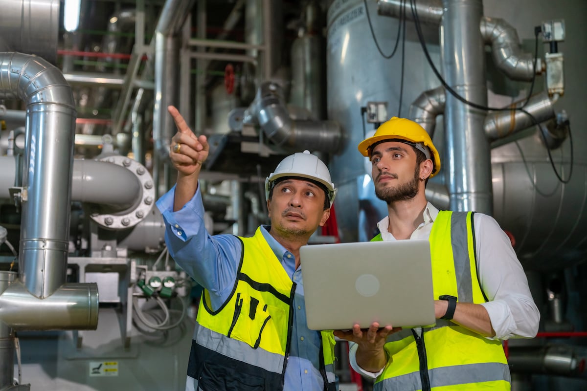 Two professional electrical engineer in safety uniform working together at factory site control room.