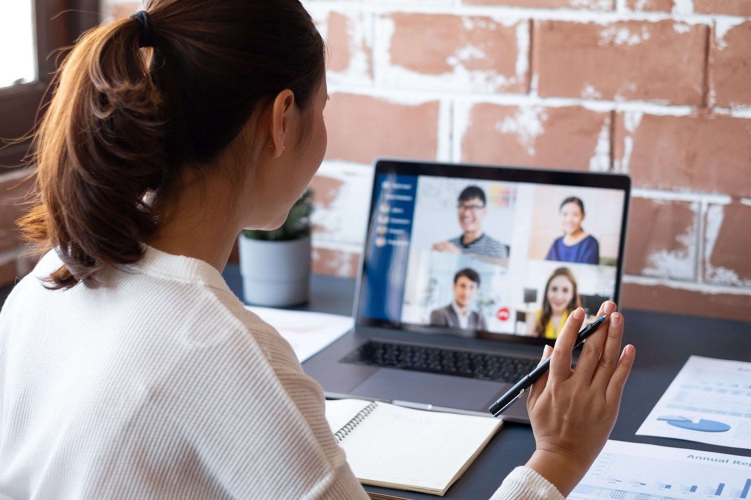 A person participates in a video conference with four participants on a laptop.