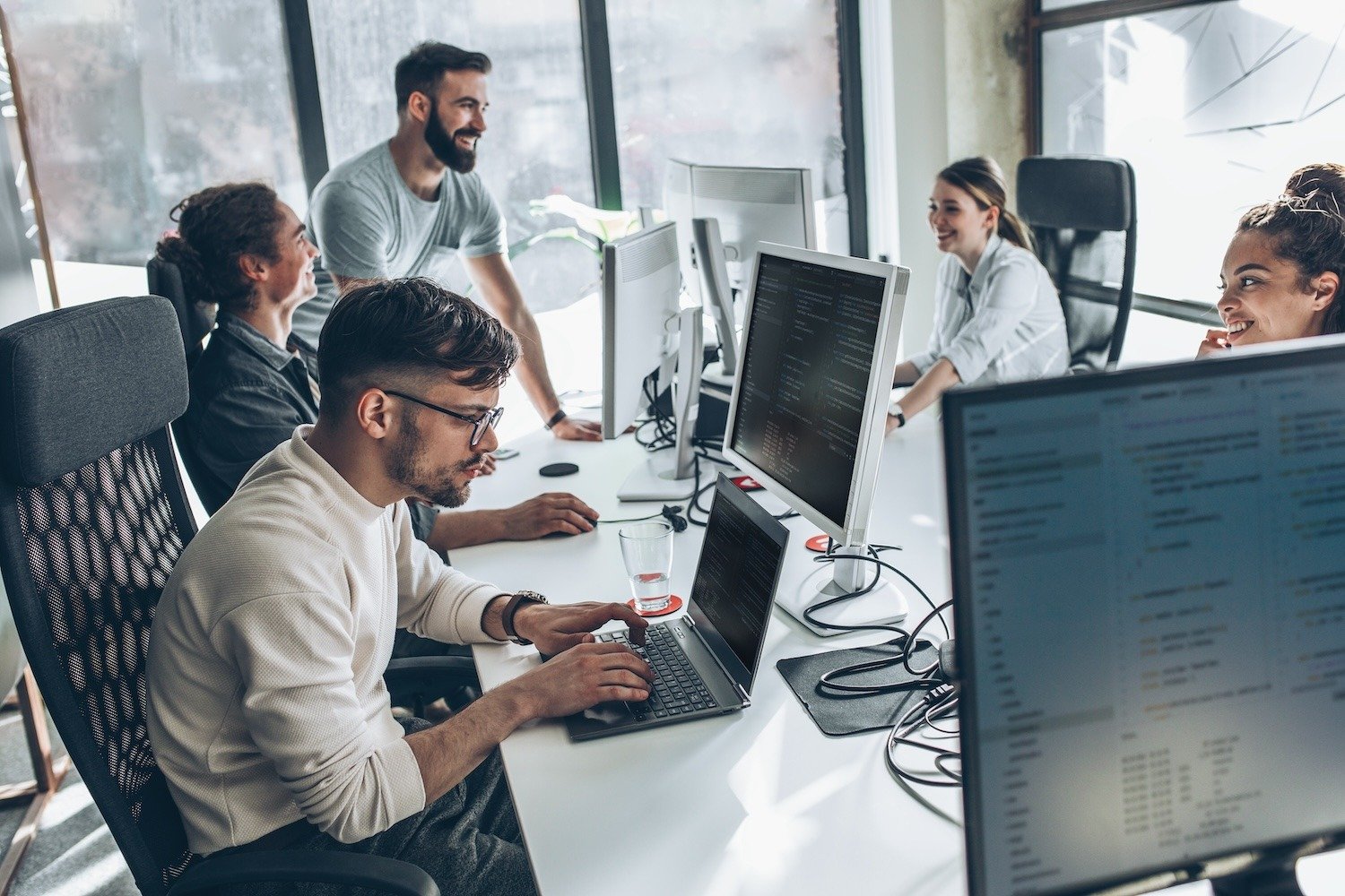 Team working in a bright office with computers and laptops.