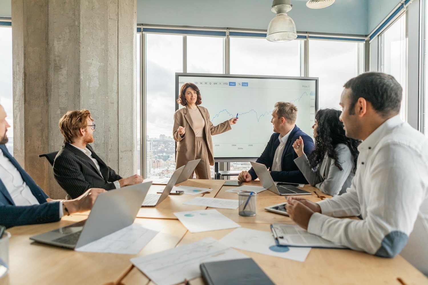 Business meeting with a woman presenting a graph to colleagues in a conference room.