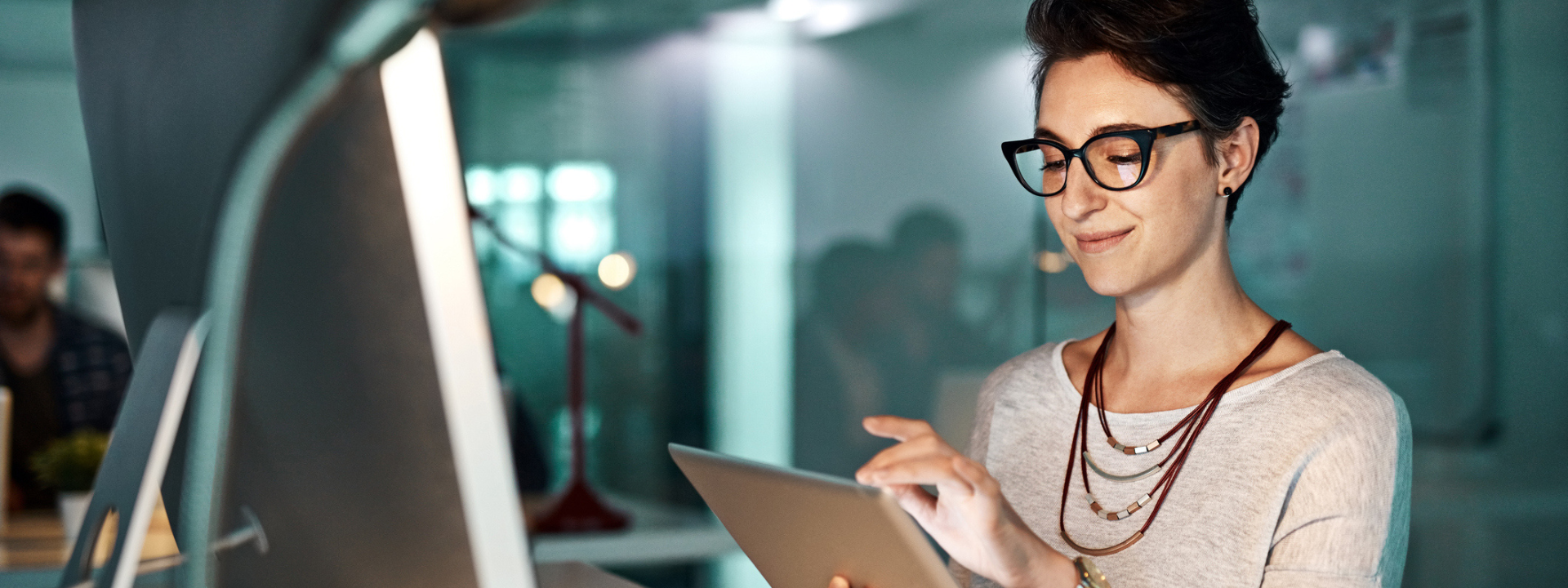 Woman at an office and smiling while working on her ipad